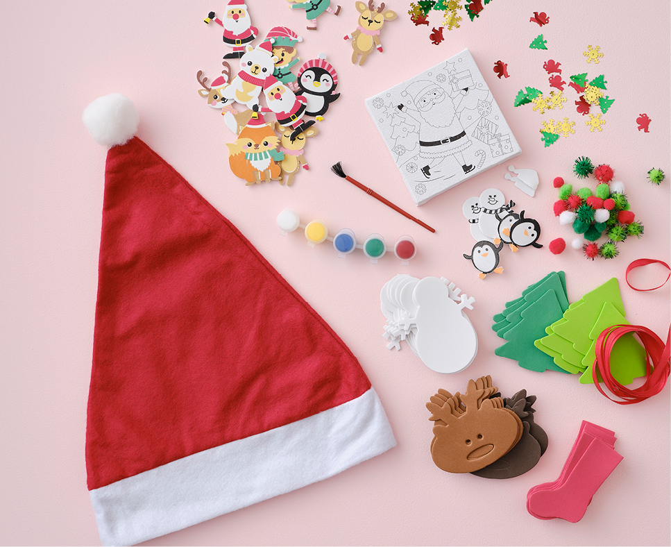 A selectin of different Christmas themed craft supplies laid out on a pink surface